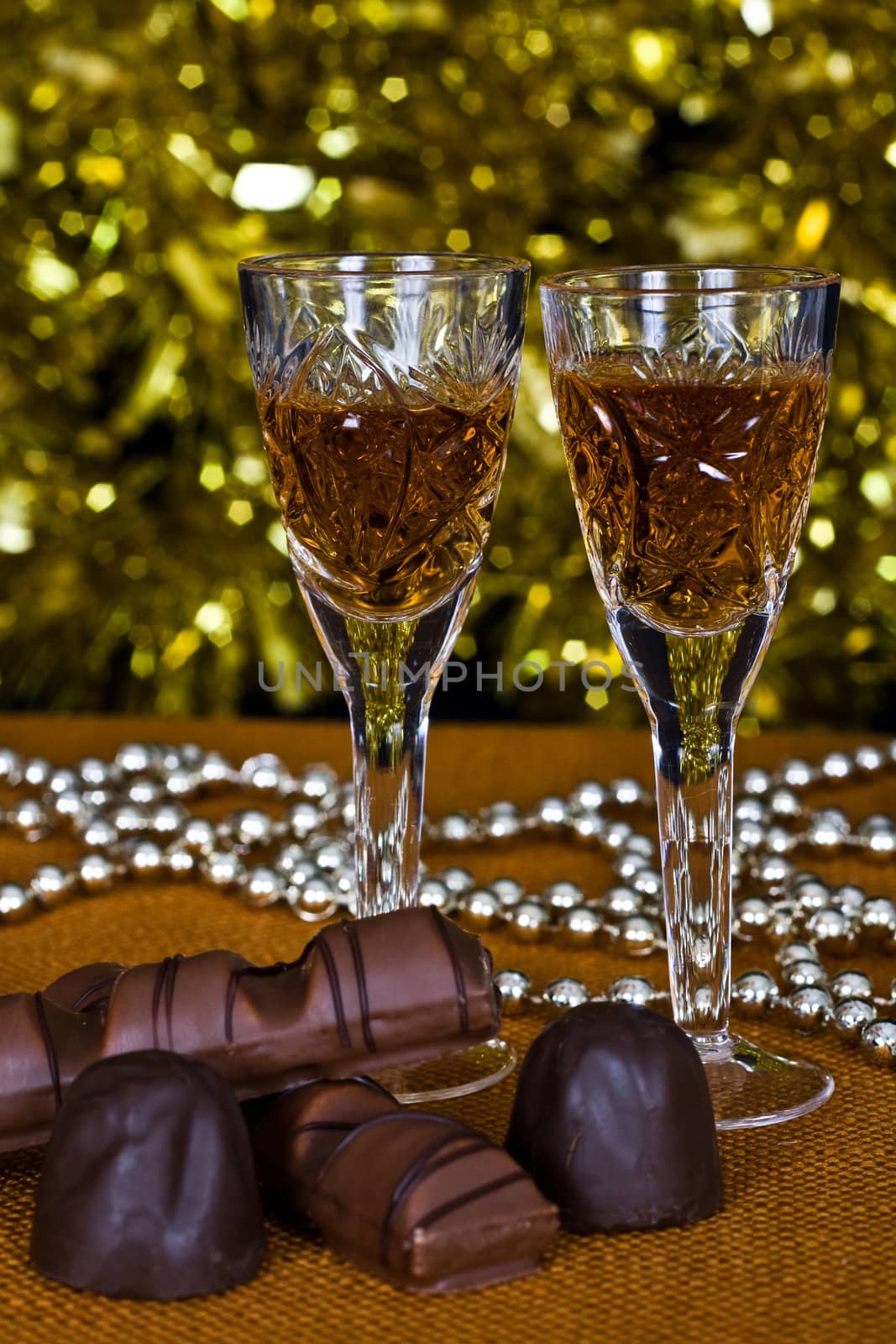 Crystal glasses of brandy and chocolate on the background of holiday lights.