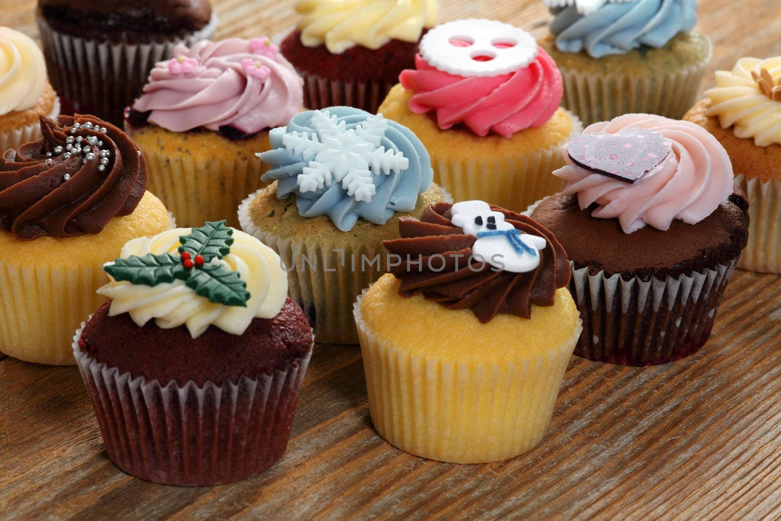 Photo of many cupcakes decorated for Christmas. Focus across the middle.
