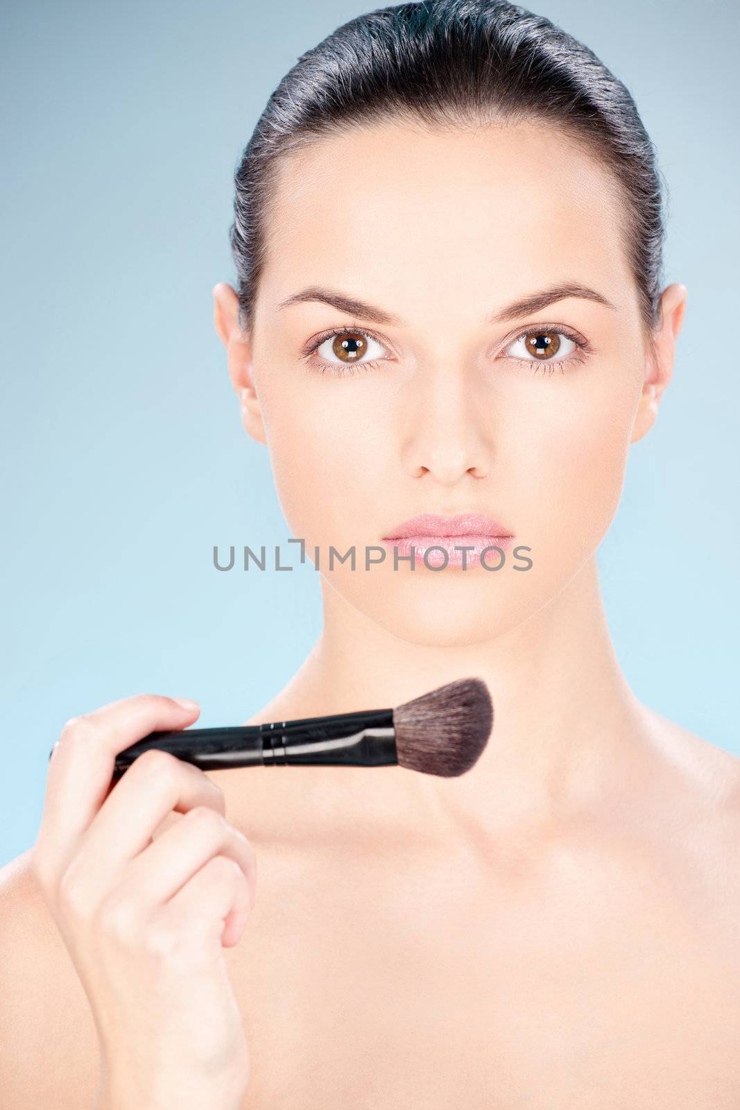 Portrait of a pretty young woman holding powder brush