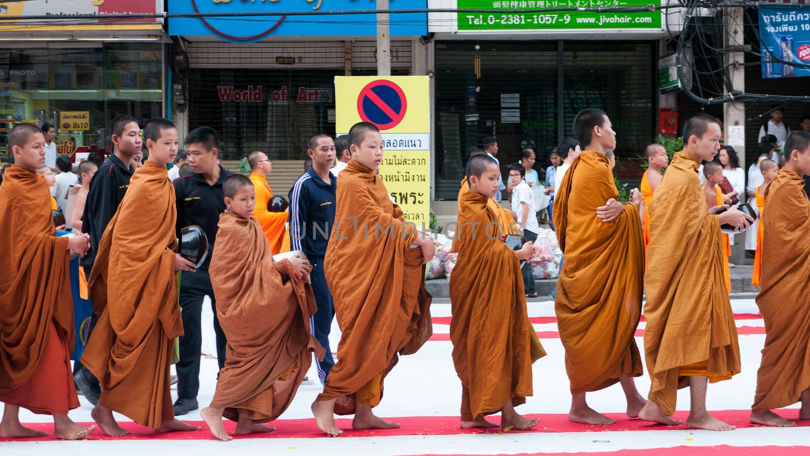 BANGKOK - DECEMBER 23: Monks participating in a mass alms giving in the morning at Soi Thonglor in celebration of the 2,600th anniversary of Lord Buddha's enlightenment on December 23, 2012 in Bangkok, Thailand.