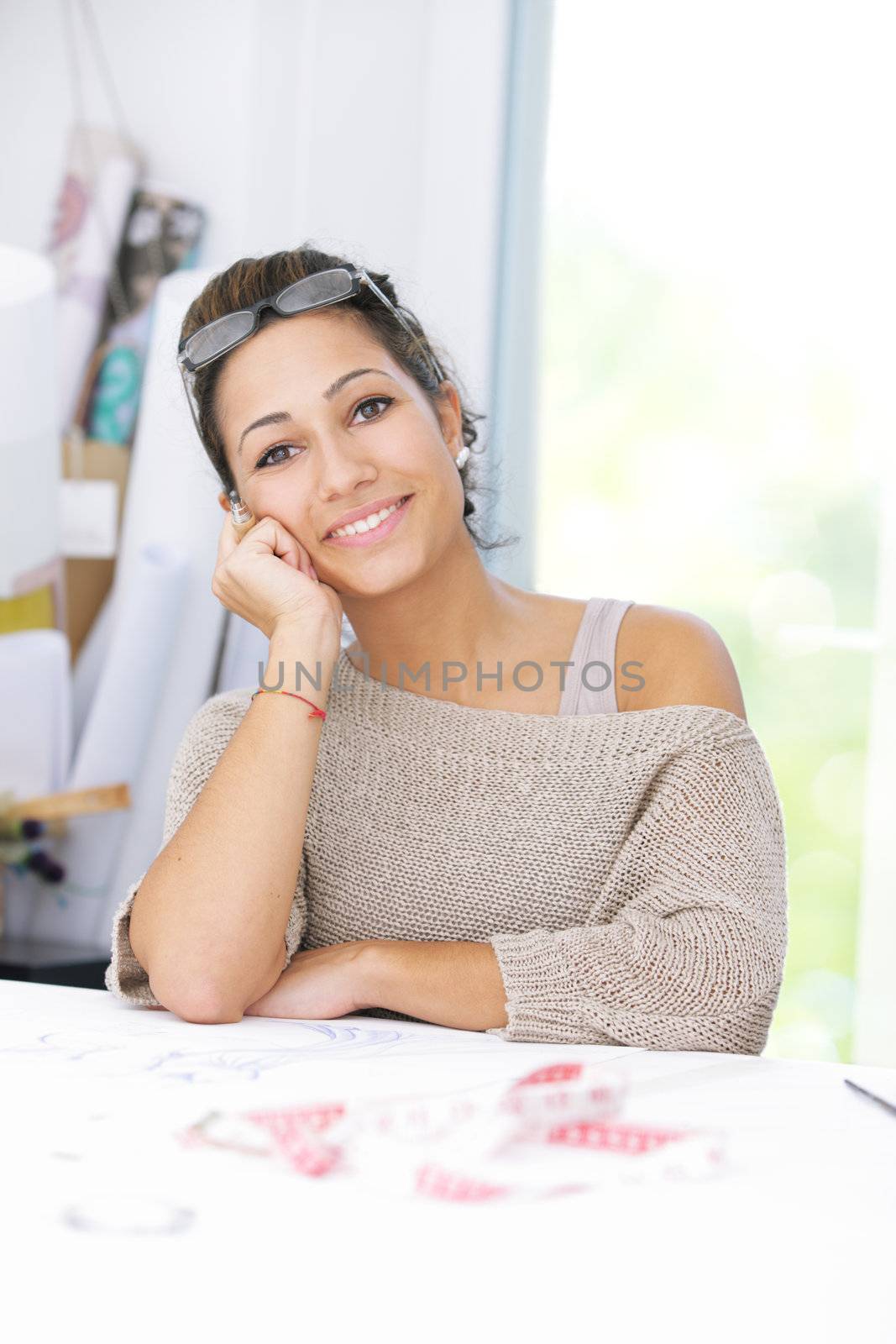 Portrait of attractive female fashion designer sitting at office desk