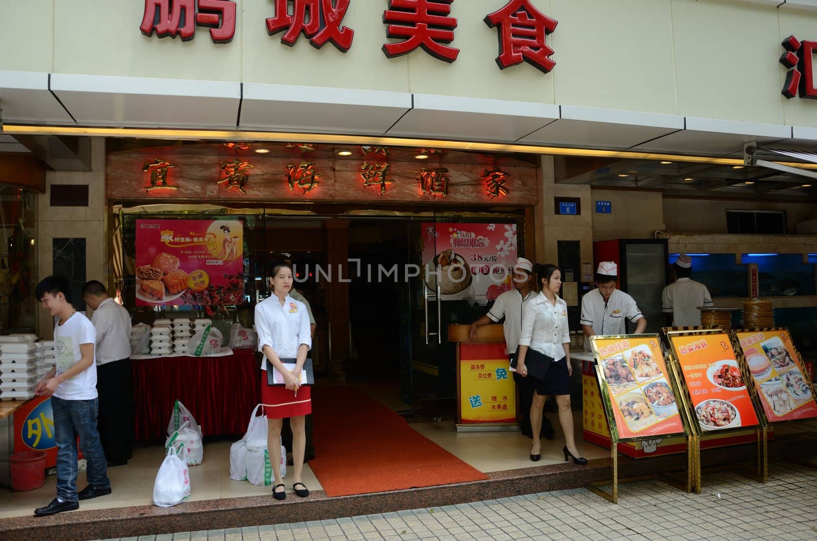 SHENZHEN, CHINA - SEPTEMBER 6:  Unidentified waitress and chefs welcome guest in front of Chinese restaurant on September 6, 2012.