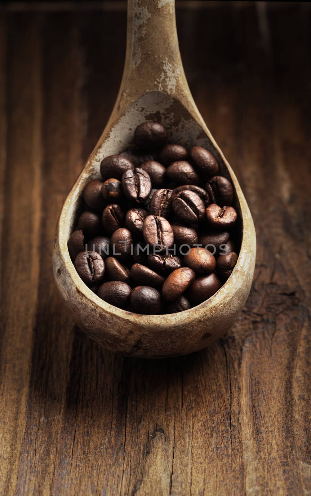 Close up of wooden spoon with coffee beans on it by stokkete