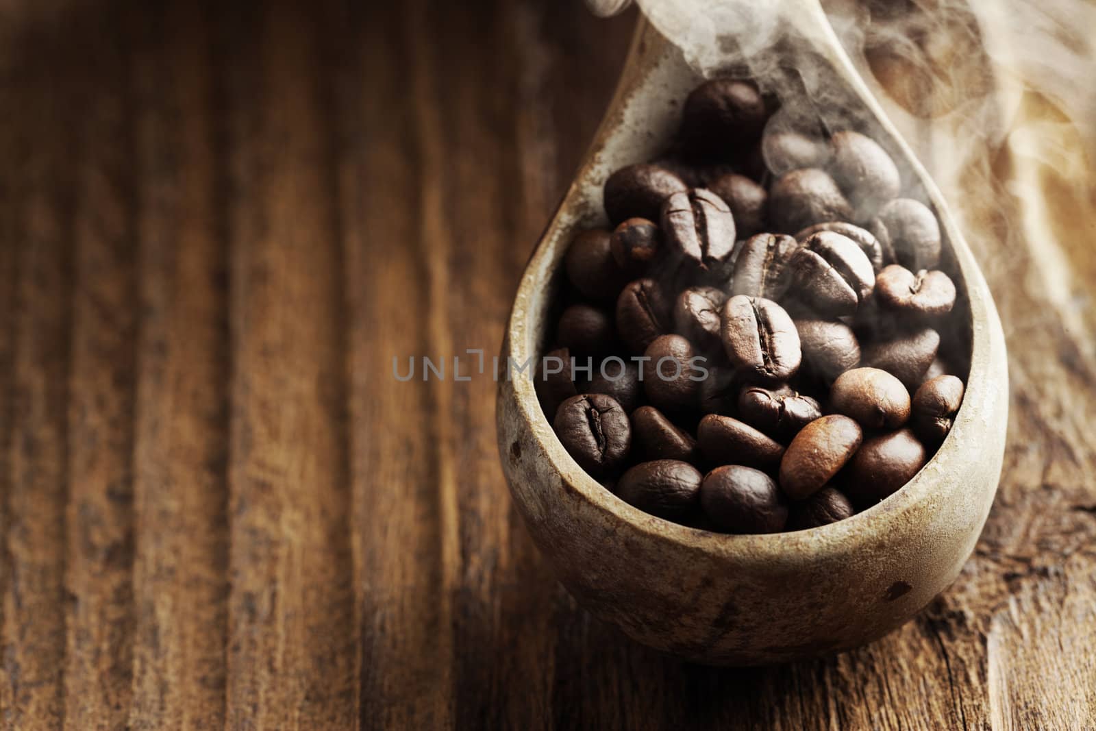 Close up of wooden spoon with coffee beans on it by stokkete