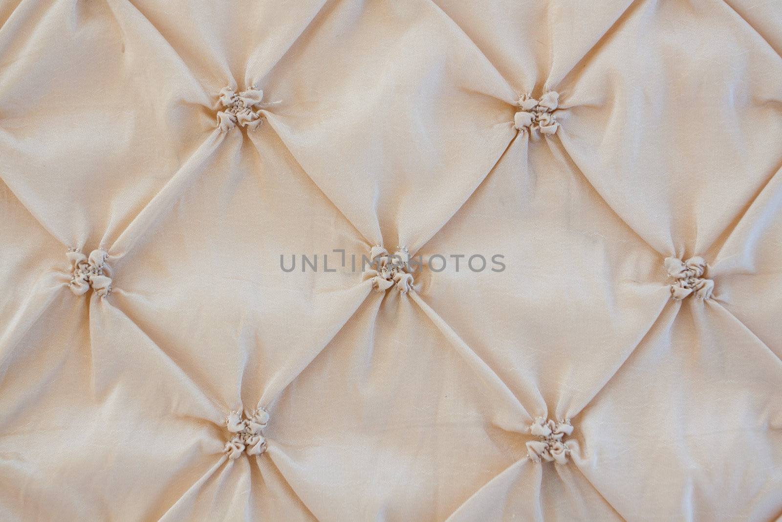 A tufted headboard with a beige tan tone to it at a wedding.