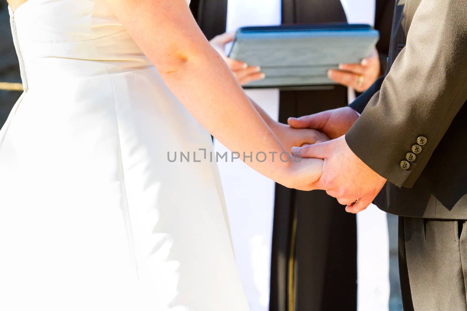 A bride and groom hold hands while reciting their wedding vows.