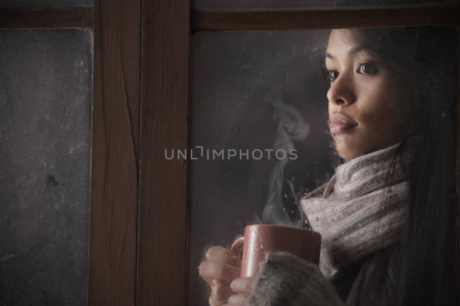 Portrait of a beautiful woman behind window with a cup of coffee or tea