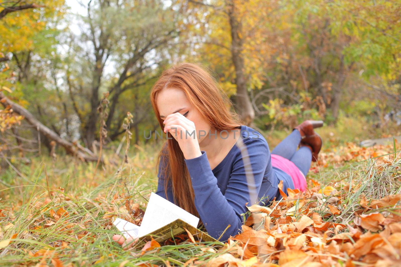 young, beautiful girl holding an open book, read background fall park