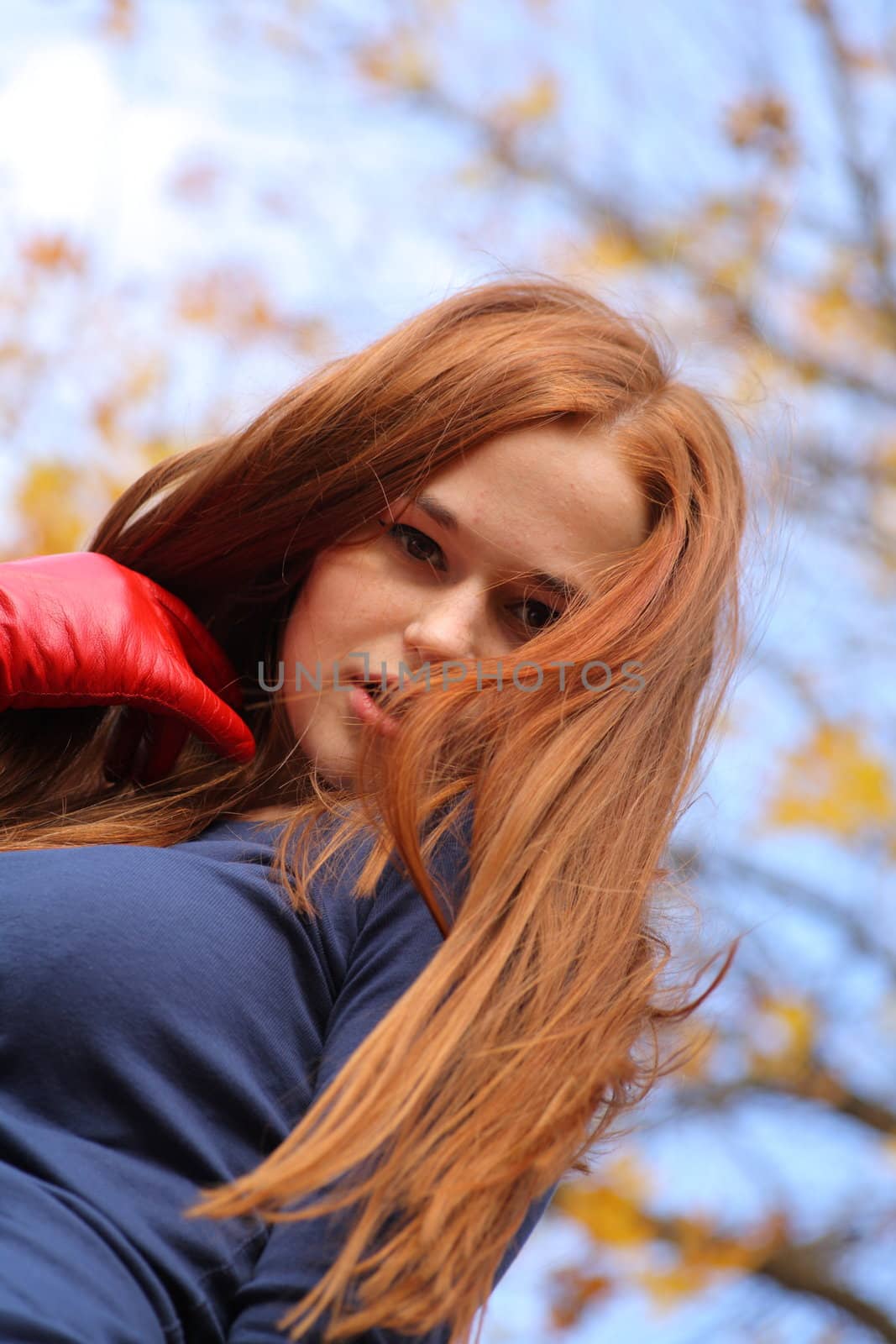 Close-up portrait of a beautiful red-headed girl posing outdoors