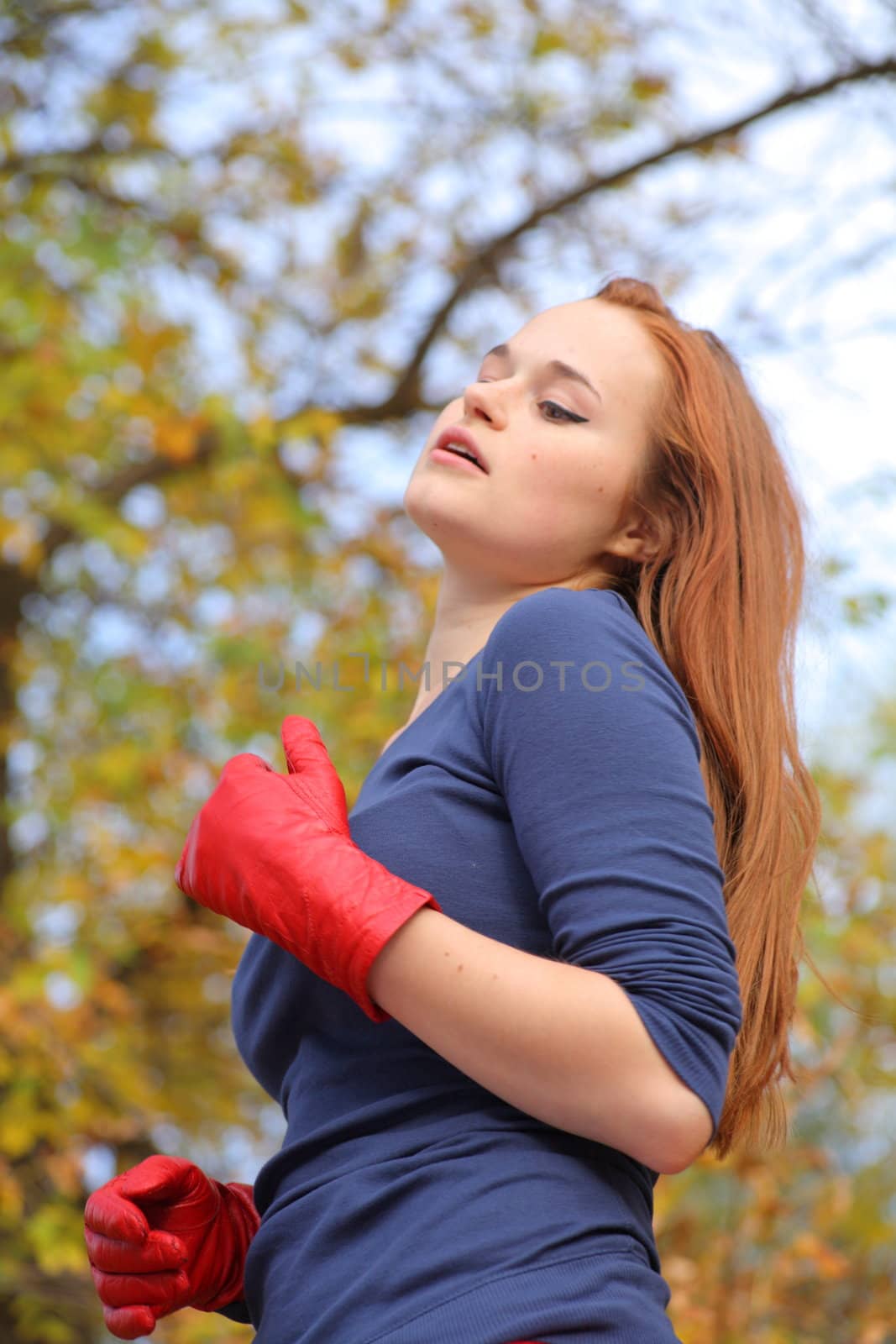 Close-up portrait of a beautiful red-headed girl posing outdoors