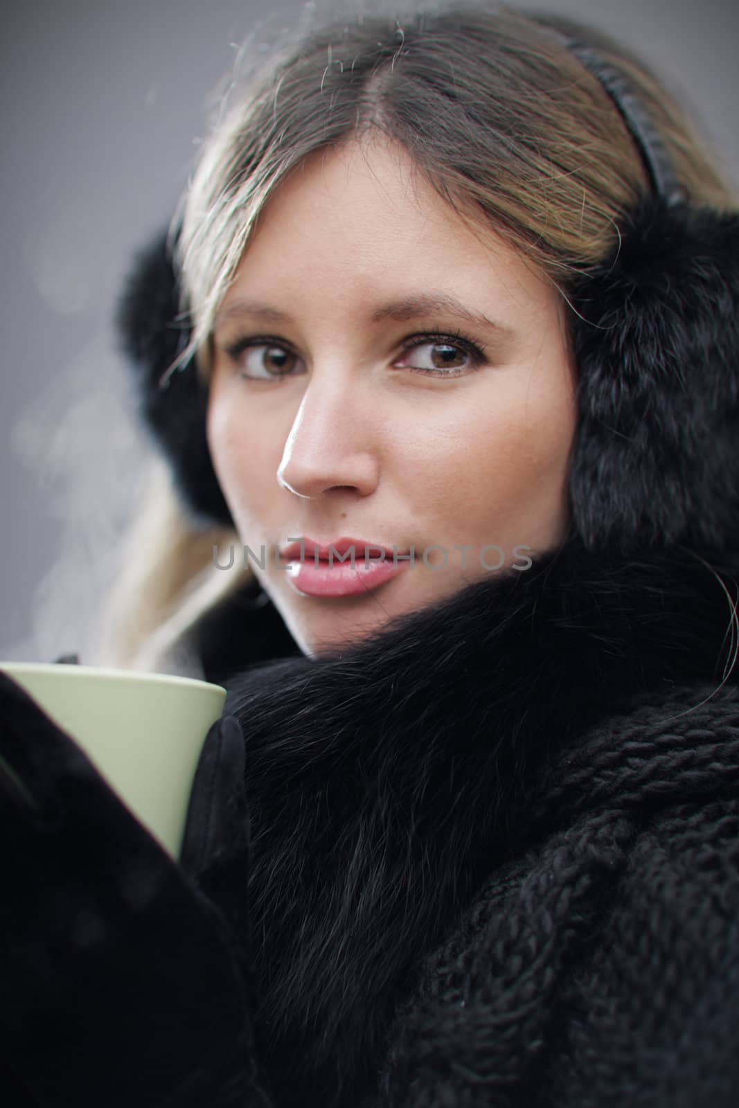 Young woman wearing winter clothes having a hot drink, shallow deep of field