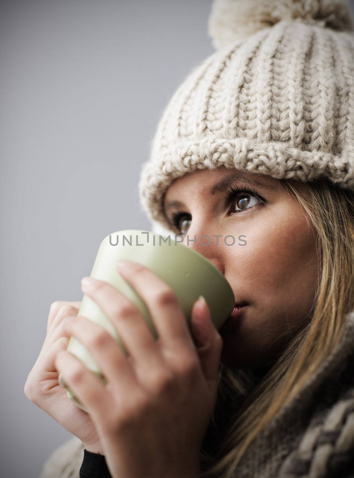 Young woman wearing winter clothes having a hot drink 