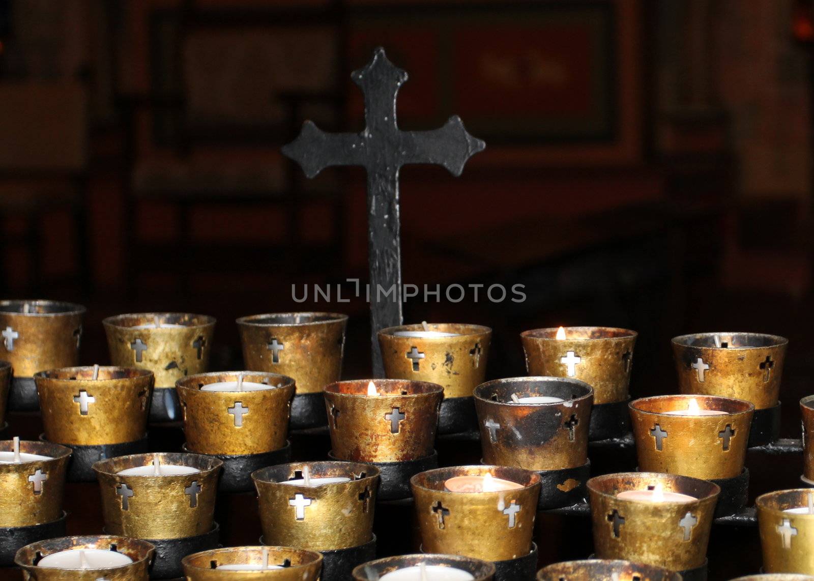 Candles in a church on black background with a cross.