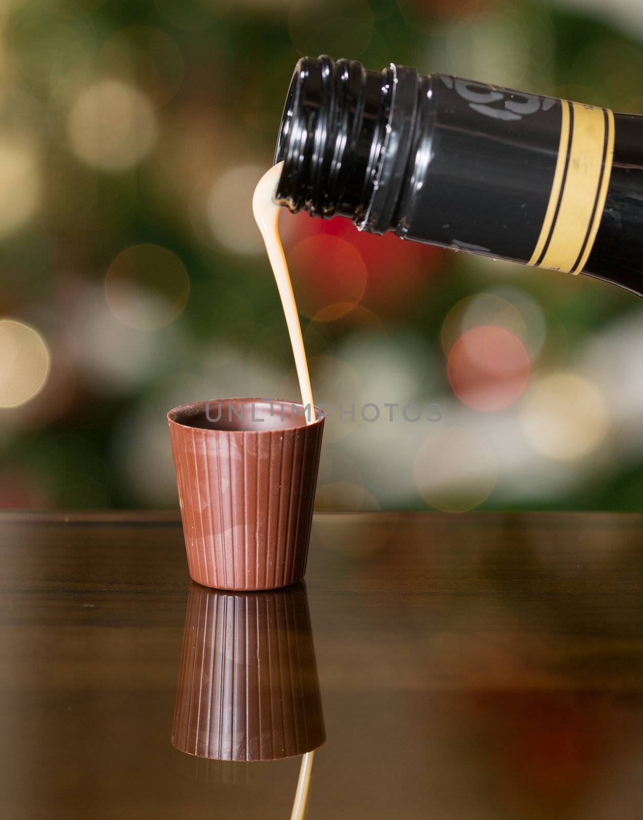 Irish cream milky liqueur being poured into chocolate shot glass with christmas tree