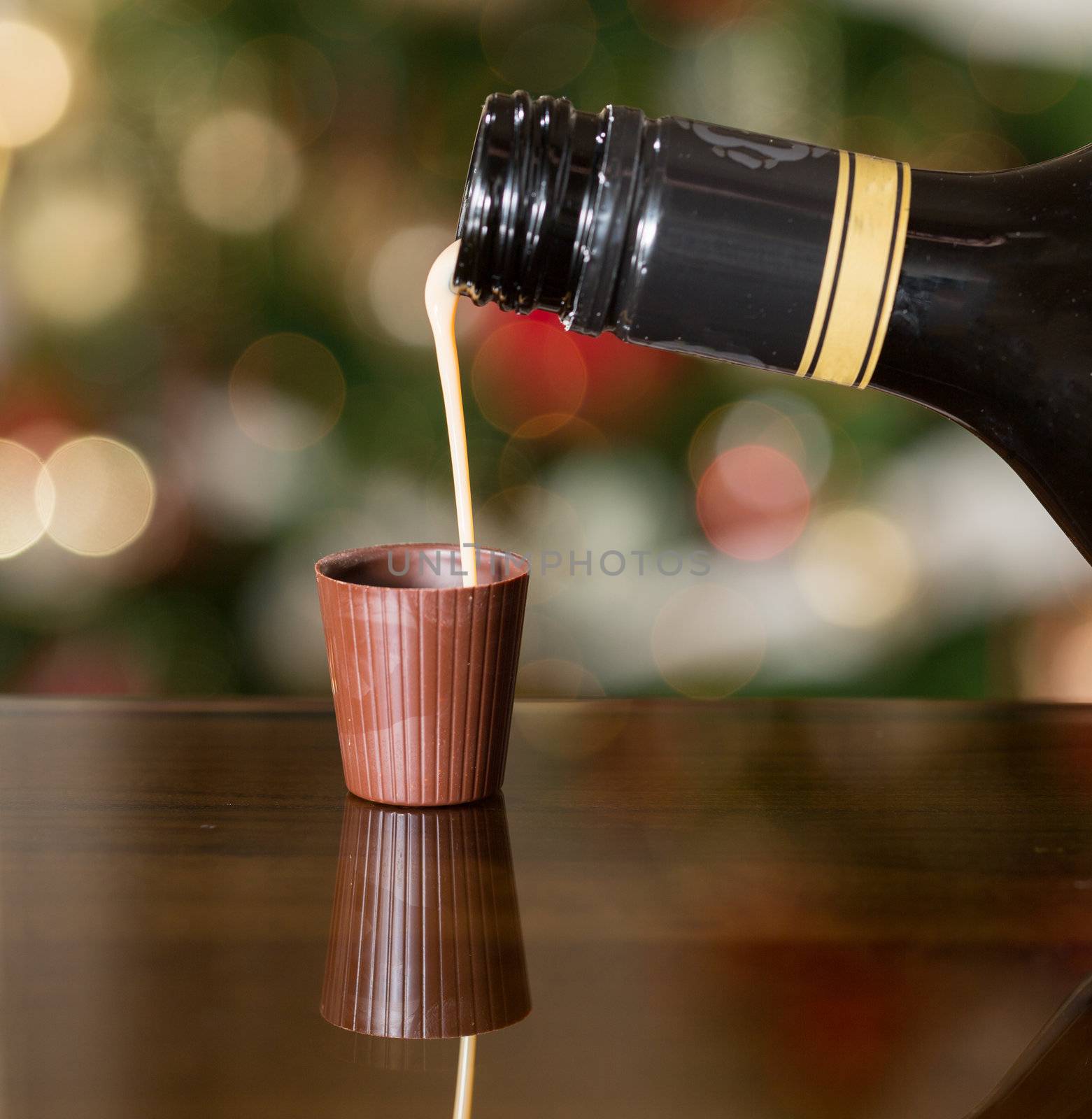 Irish cream milky liqueur being poured into chocolate shot glass with christmas tree