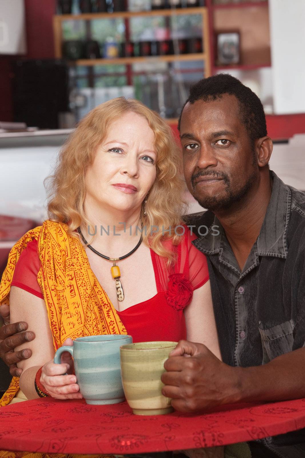 Calm black and white couple with mugs in restaurant