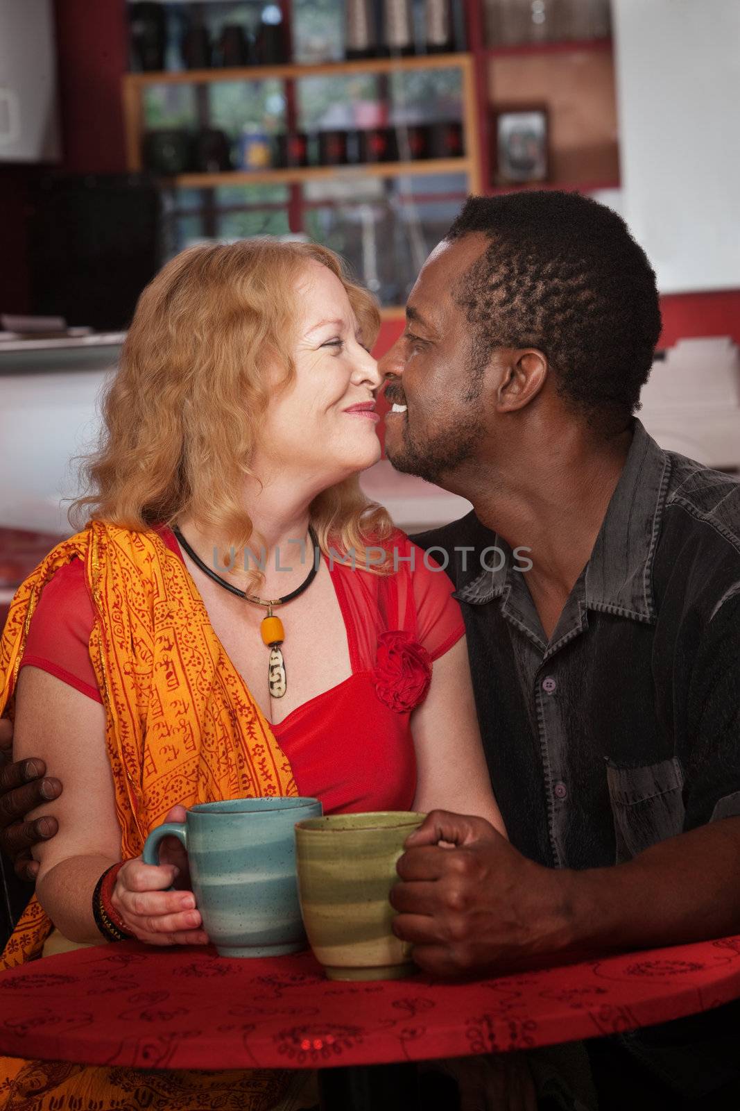 Mixed middle aged couple do an Eskimo Kiss in cafe