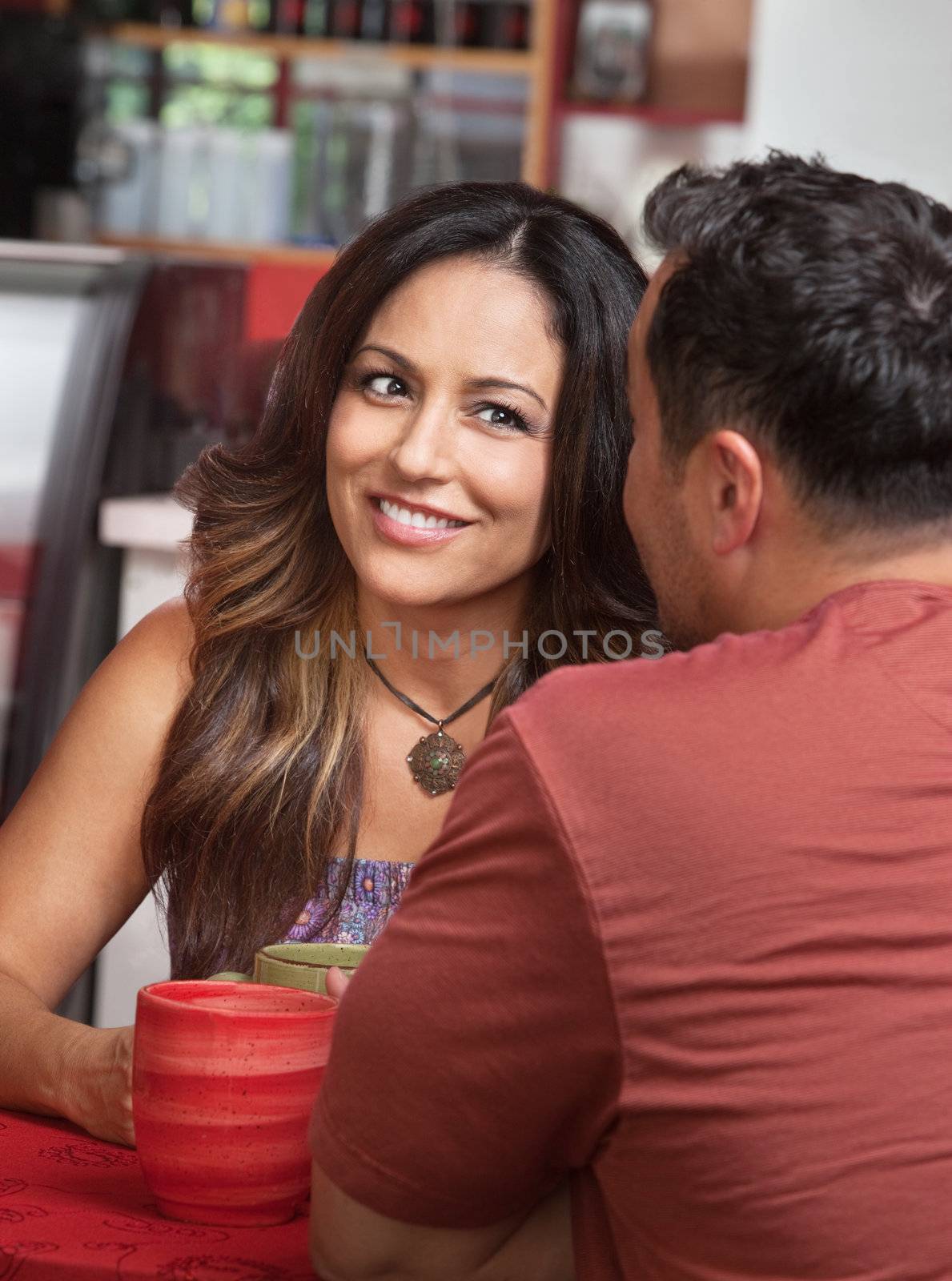 Skeptical Hispanic woman listening to man talk in cafe