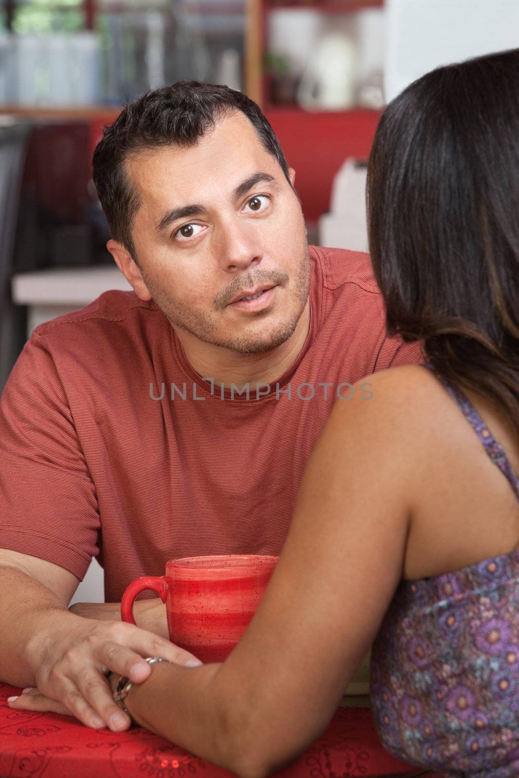 Hispanic man comforting female and holding her hand in cafe
