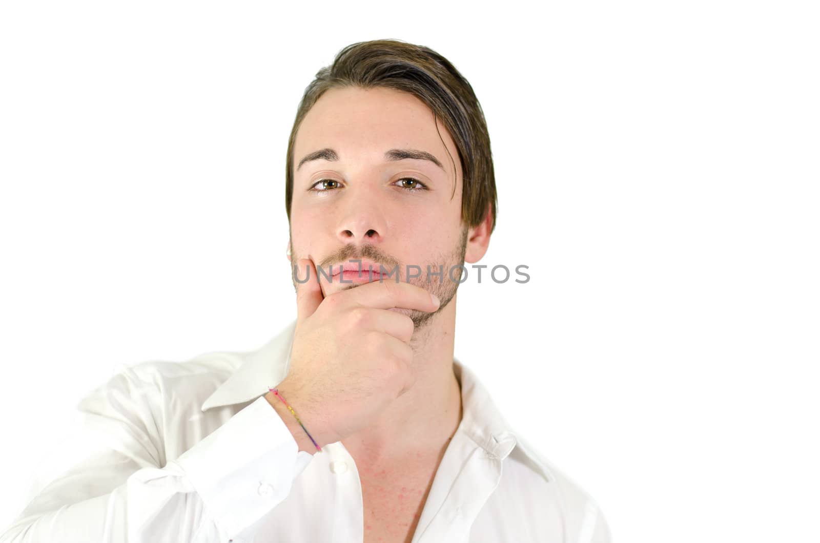 Attractive young man holding his chin, looking at camera and thinking