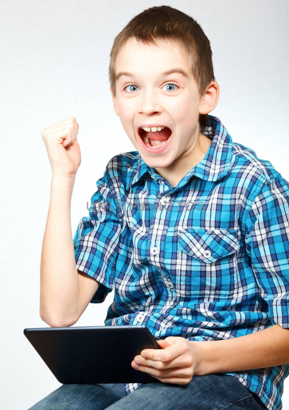 Young boy pumps his fist and cheers holding a touch pad