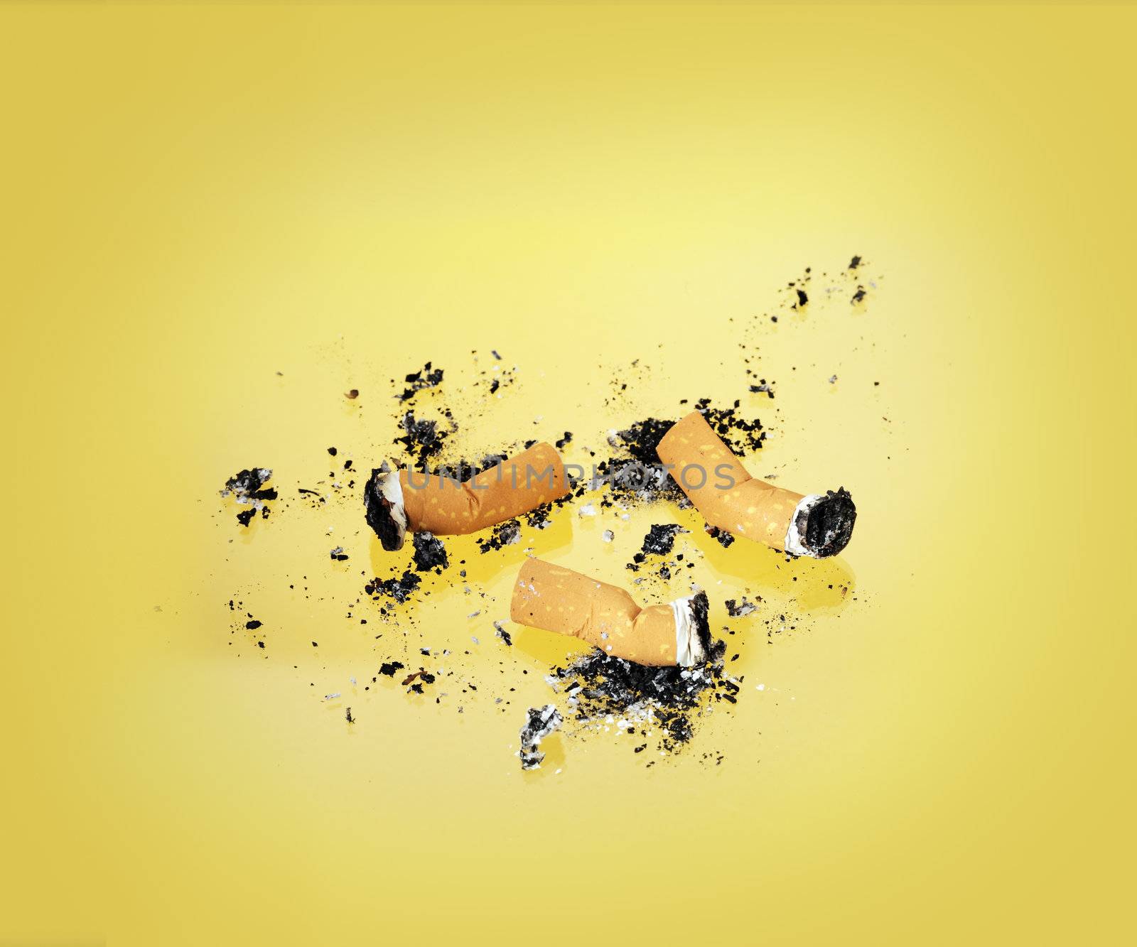 Burnt cigarette butts on yellow background.