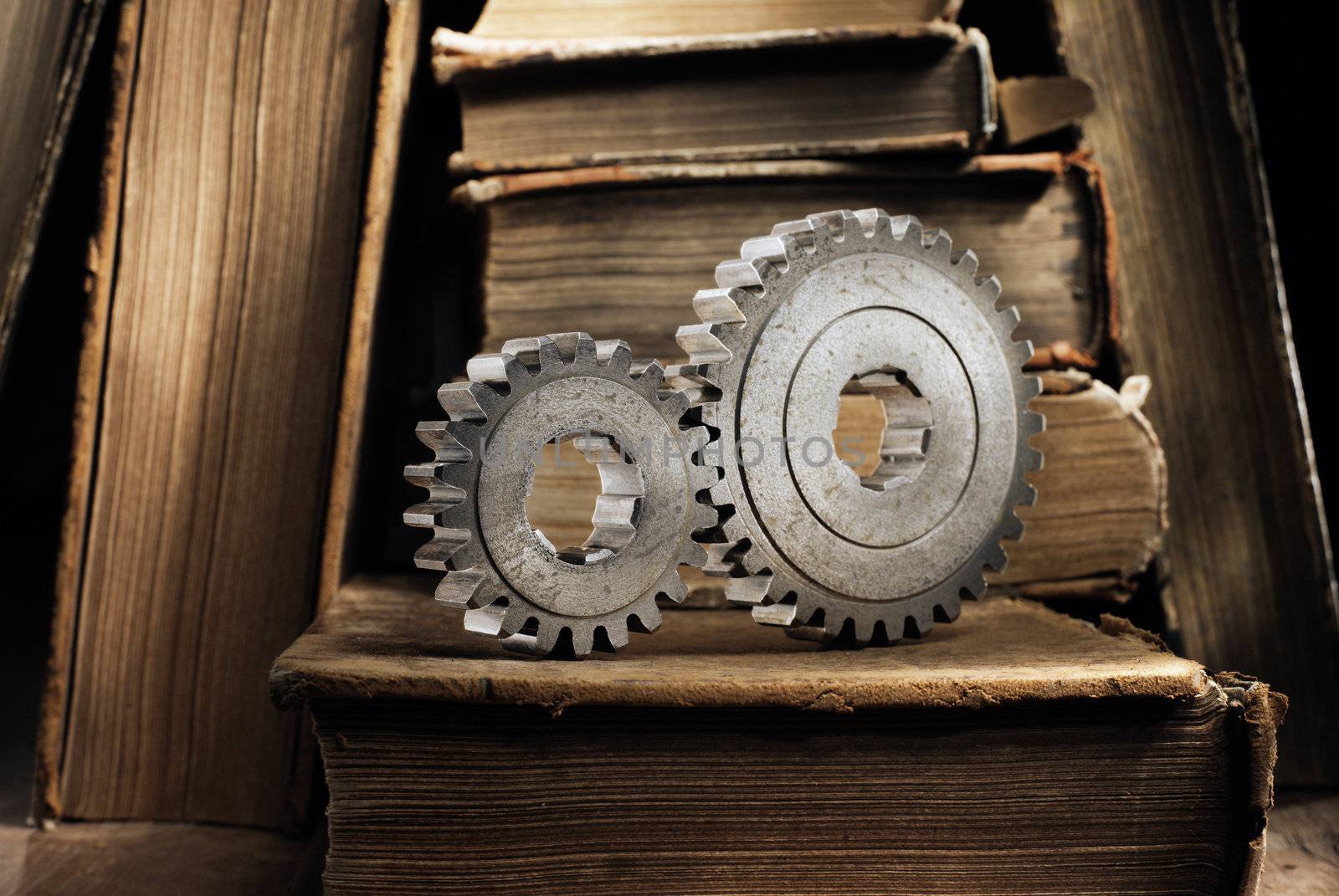 Still life with old metallic cog gears and antique books. Short depth of field.