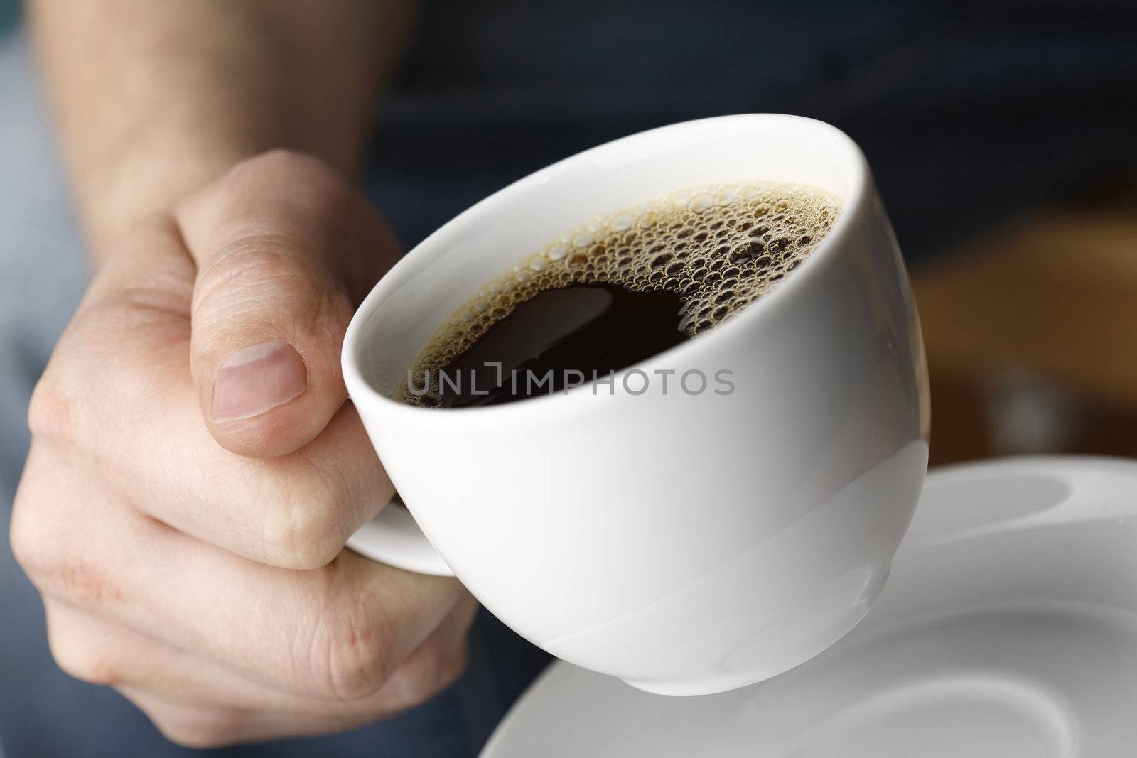 Hand with a cup of fresh black coffee.