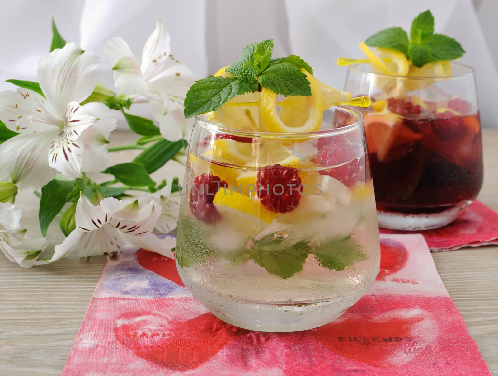 A glass of fresh homemade lemonade with mint and raspberries