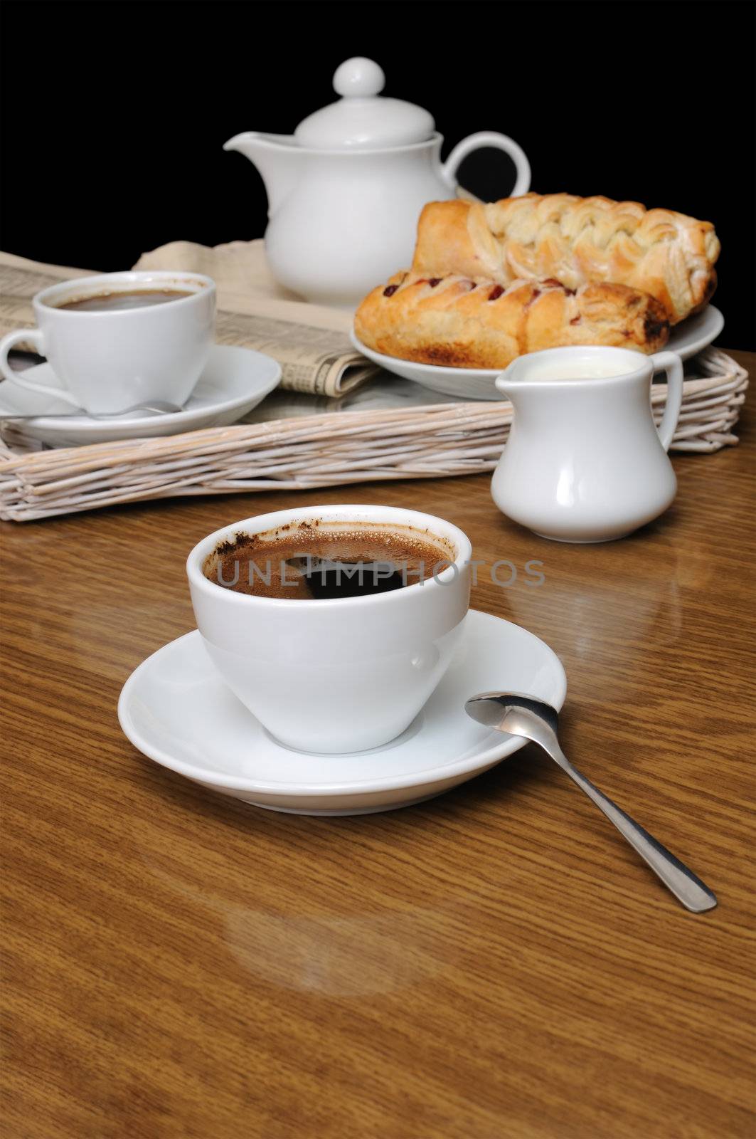 A cup of black coffee with a milkman with pies on a tray with newspaper