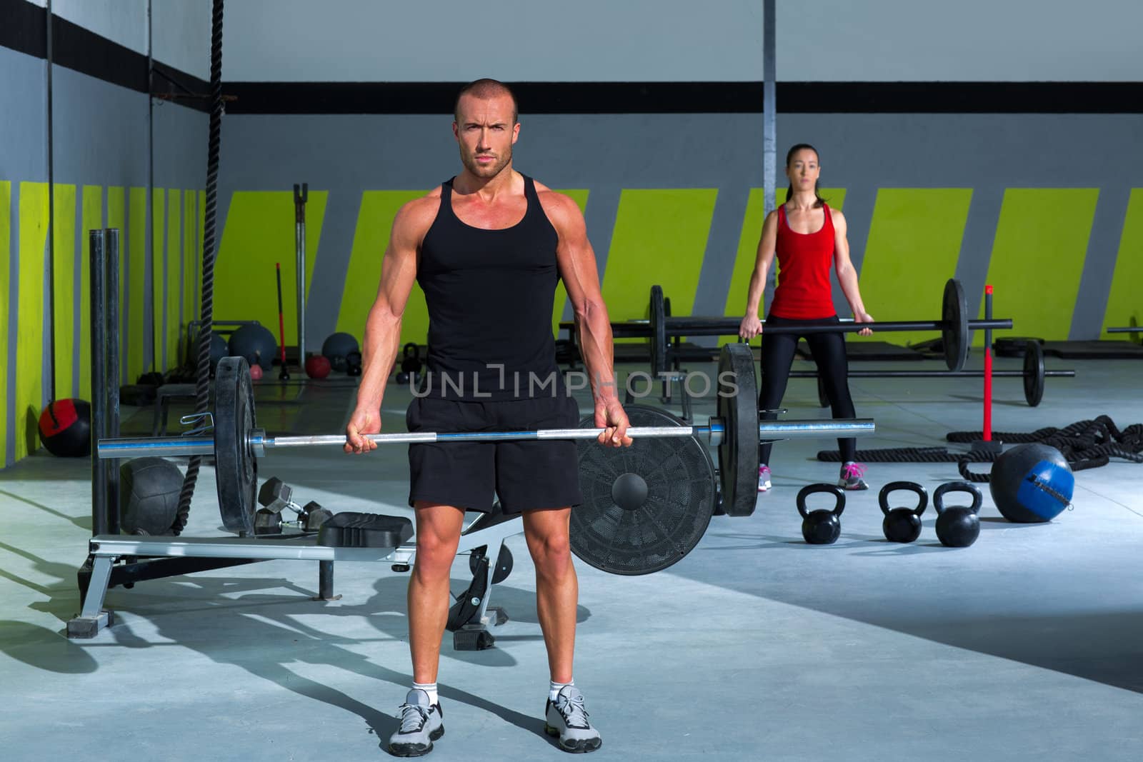 gym man and woman with weight lifting bar workout in crossfit exercise