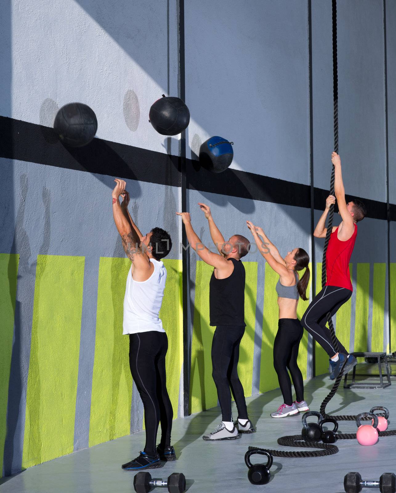 Crossfit workout people group with wall balls and rope at fitness gym