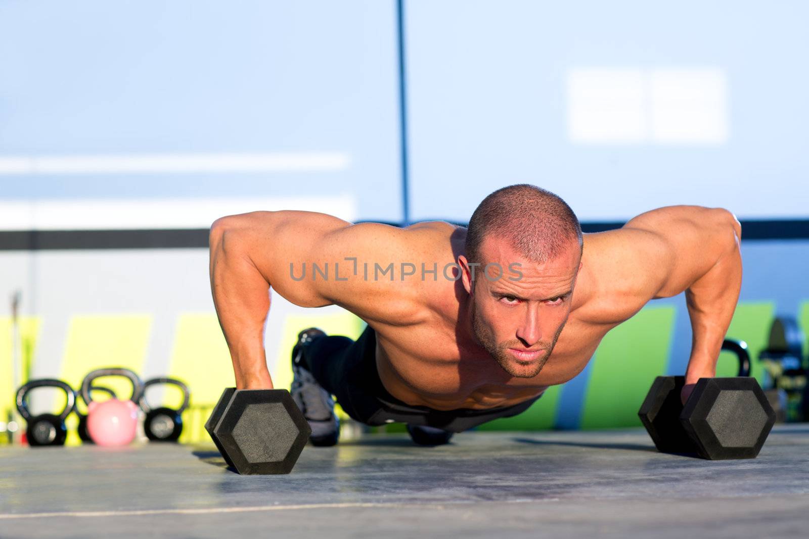 Gym man push-up strength pushup exercise with dumbbell in a crossfit workout