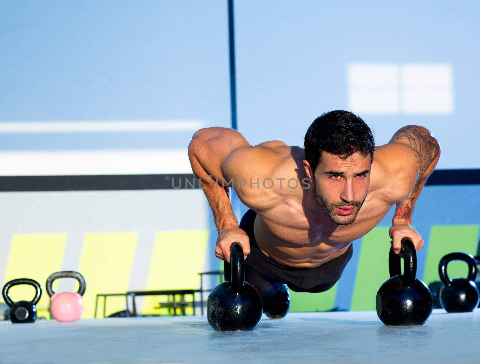 Gym man push-up strength pushup exercise with Kettlebell in a crossfit workout