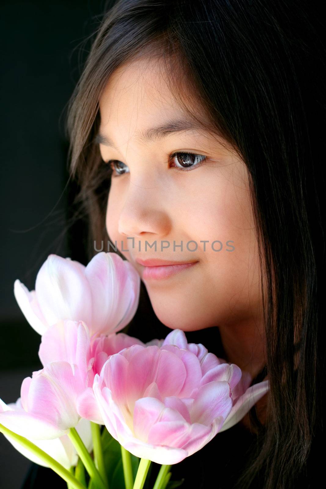 Beautiful little girl with pink tulips by face by jarenwicklund
