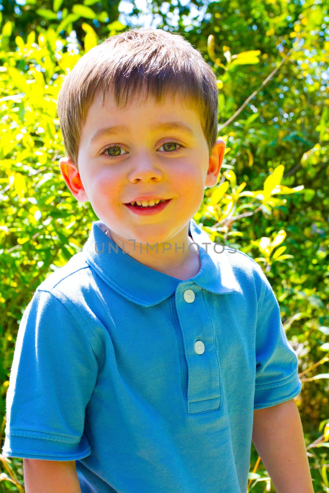 A young boy is playing outdoors while wearing a blue polo shirt.