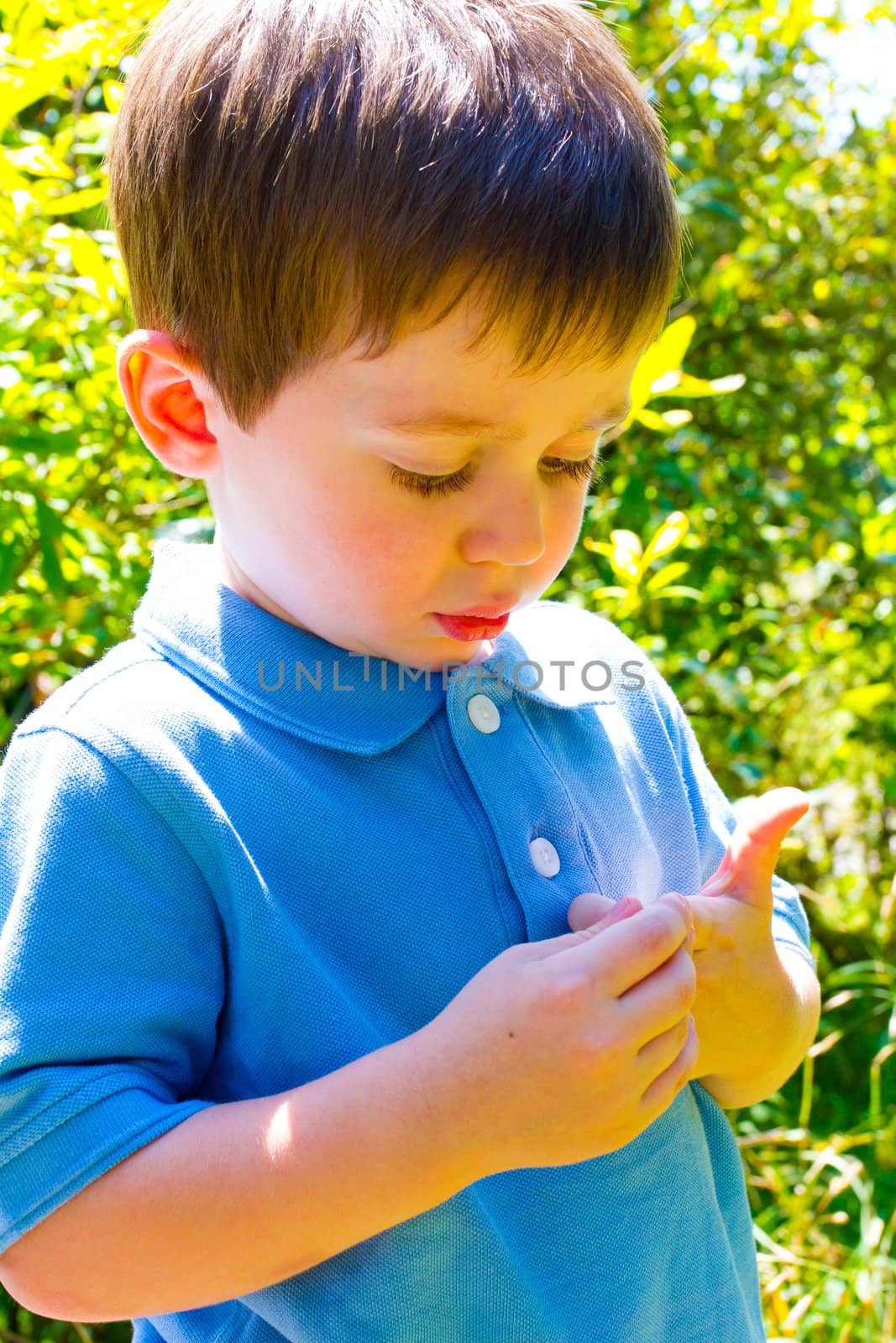 A young boy is playing outdoors while wearing a blue polo shirt.