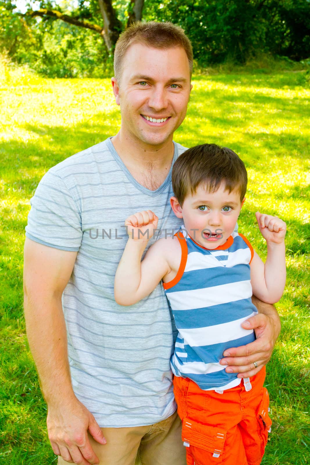 A father has his arm around his son outdoors.