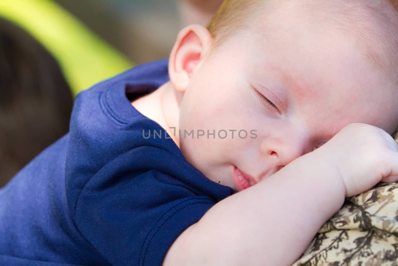 A baby that is asleep wearing a blue shirt resting.