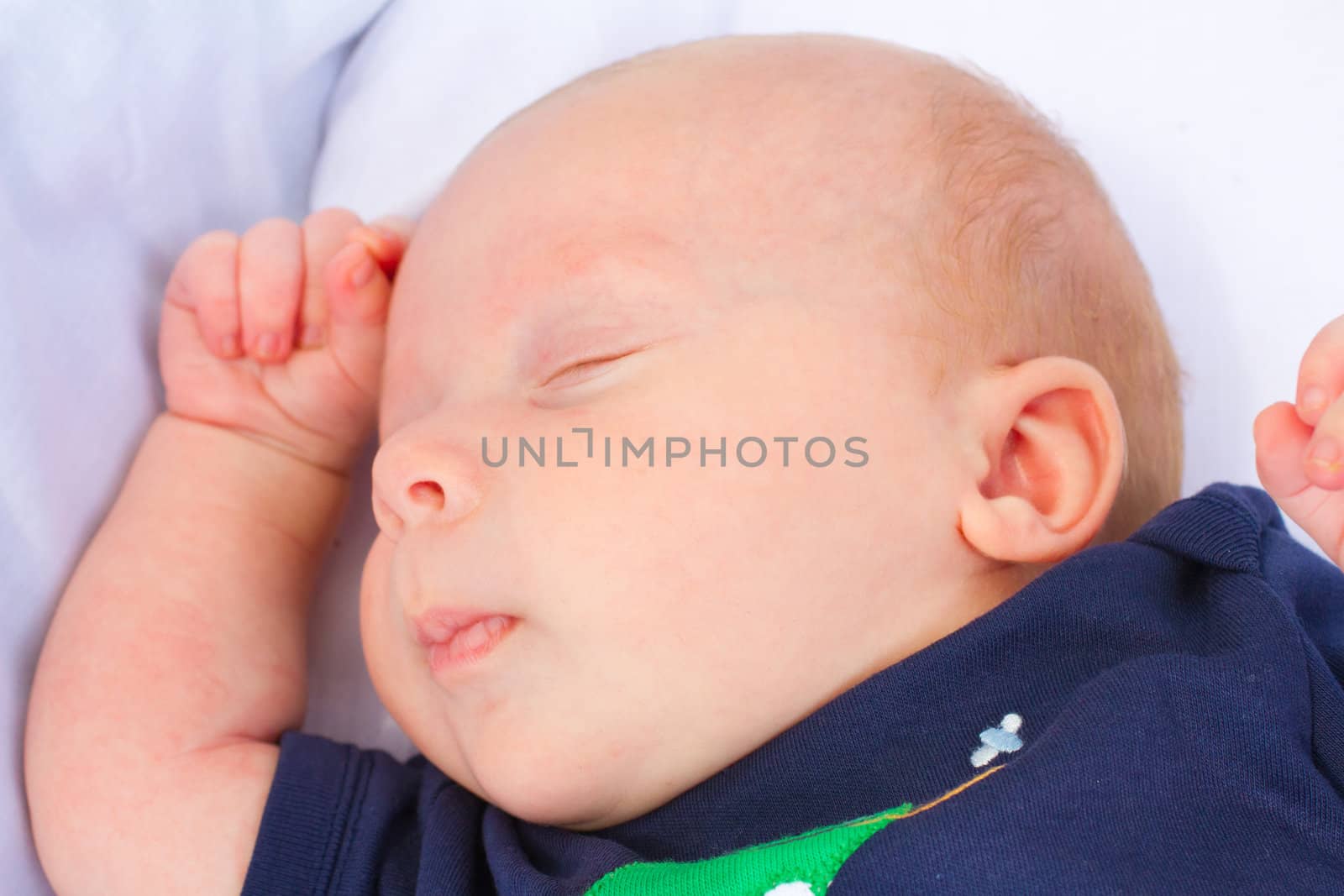 A baby that is asleep wearing a blue shirt resting.