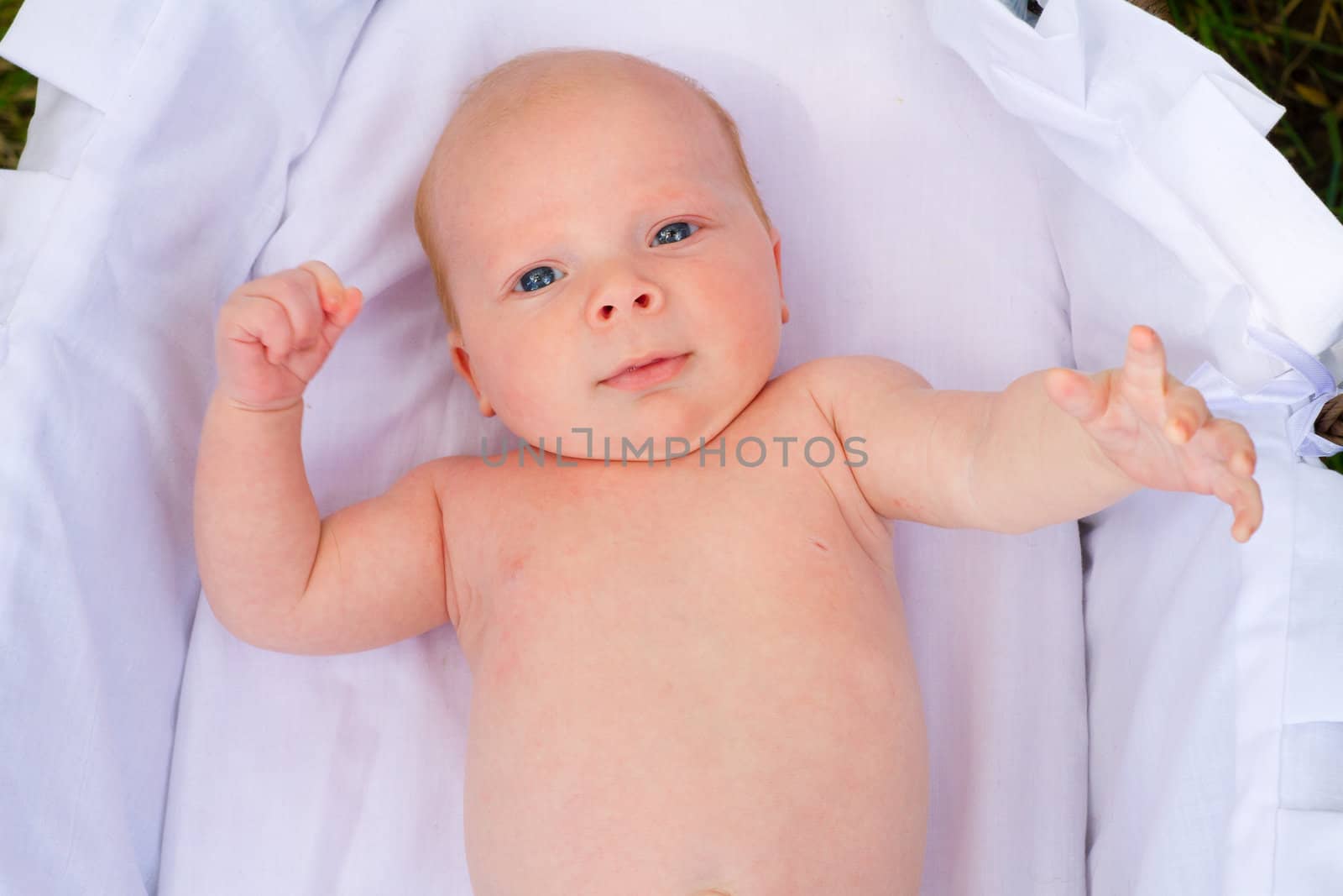 A newborn baby is looking around with his eyes open.