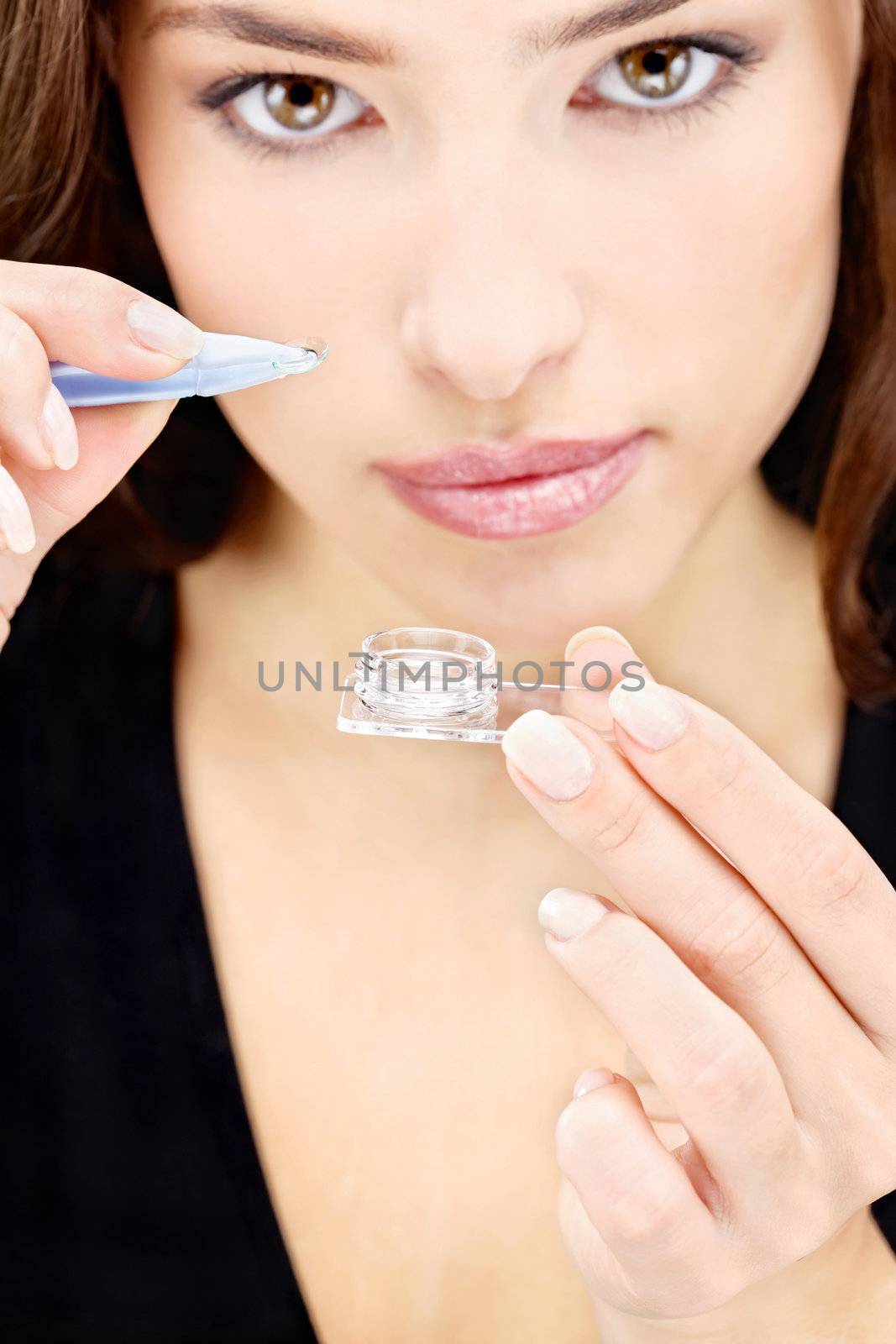 Close up of a  woman holding contact lens in front of her eye