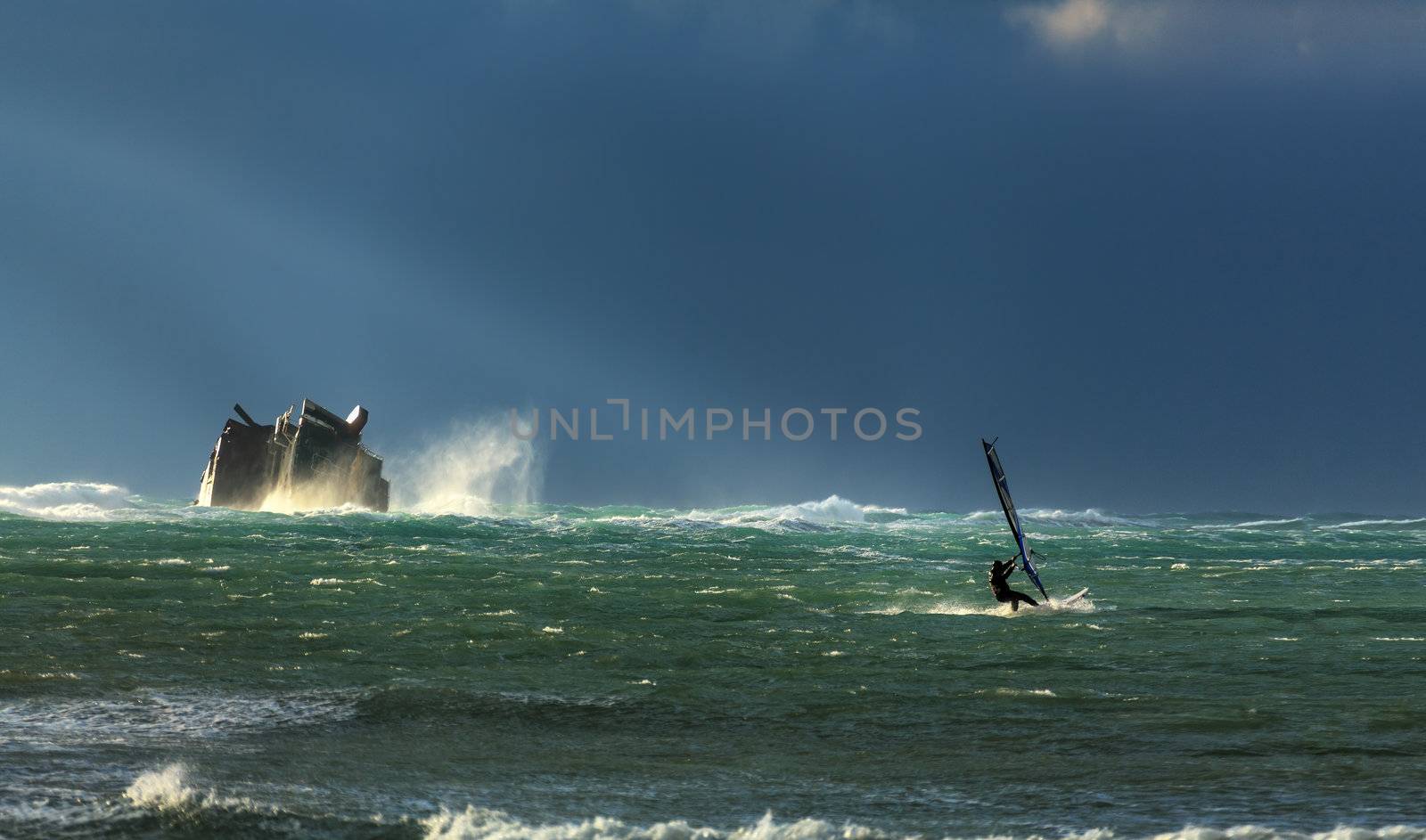 A surfer rides the storm, near the sunken ship