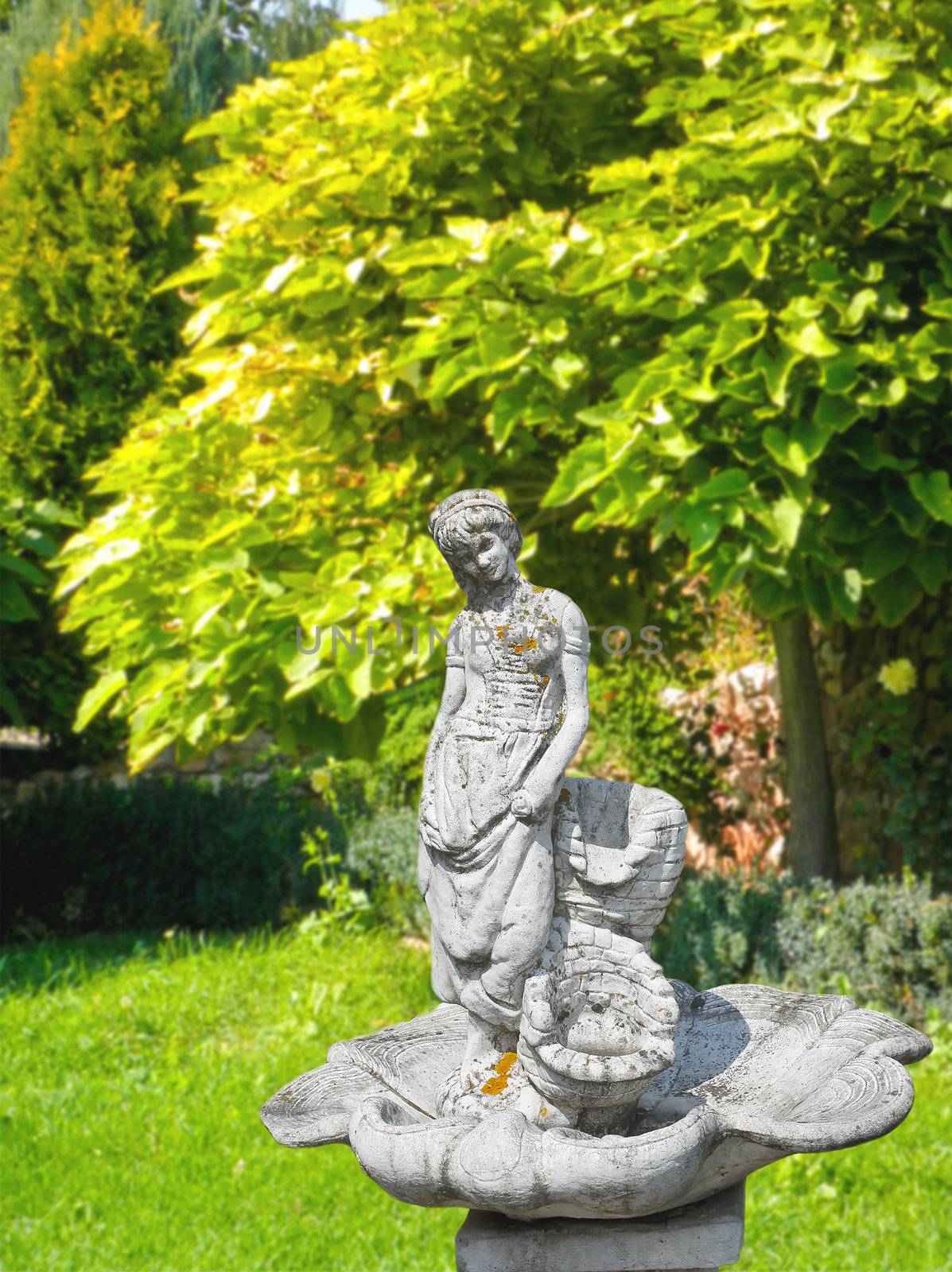 Old statue of a fountain in a shady park by NickNick