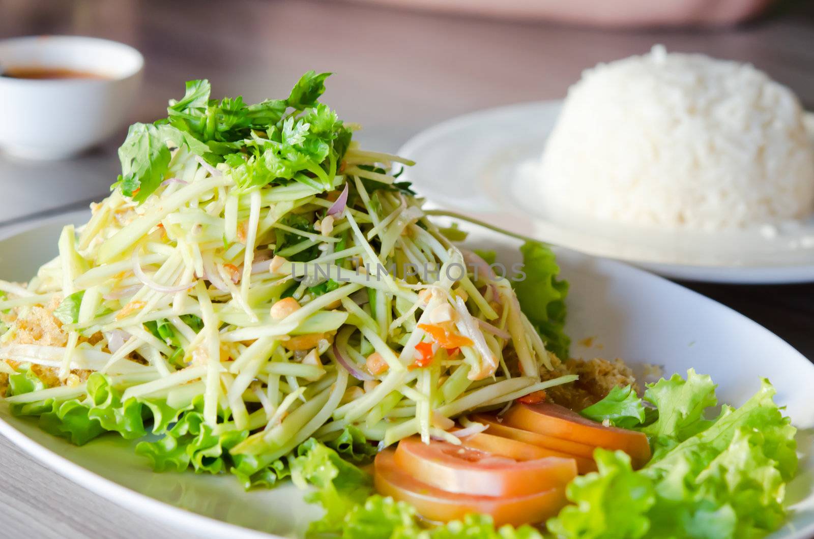 spicy crispy catfish salad with green mango and vegetable on plate served with rice