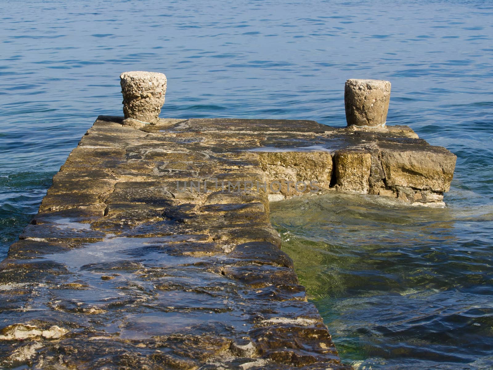 stone breakwater with two stone bitts at the peacefull adriatic sea
