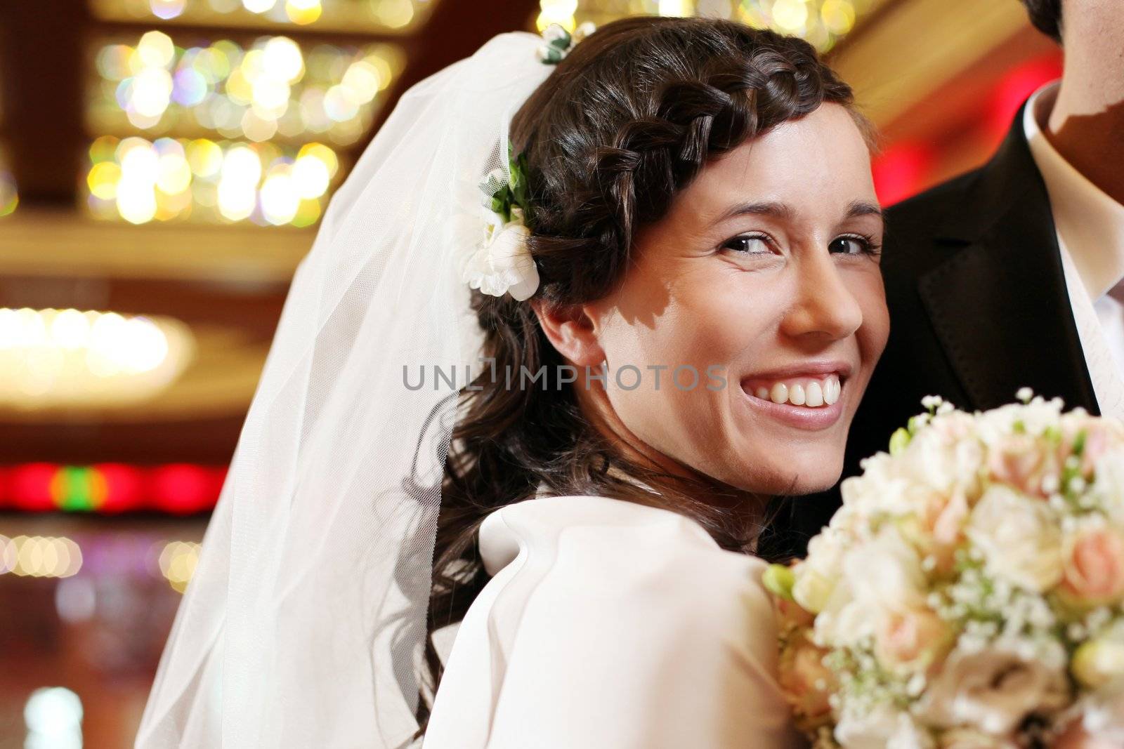 Beautiful and happy couple with flowers in hands get married indoors