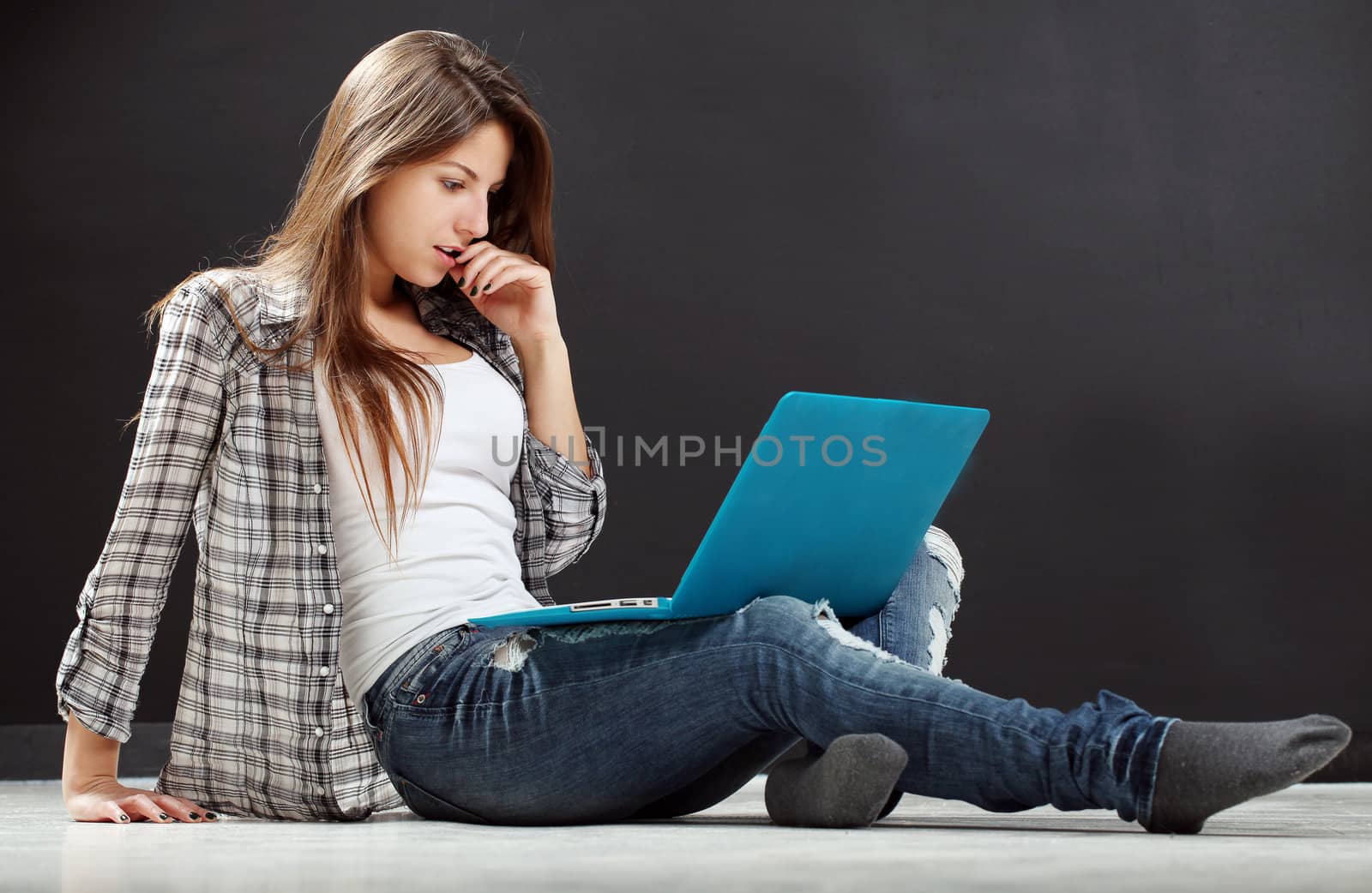 Attractive woman with laptop on the floor in studio