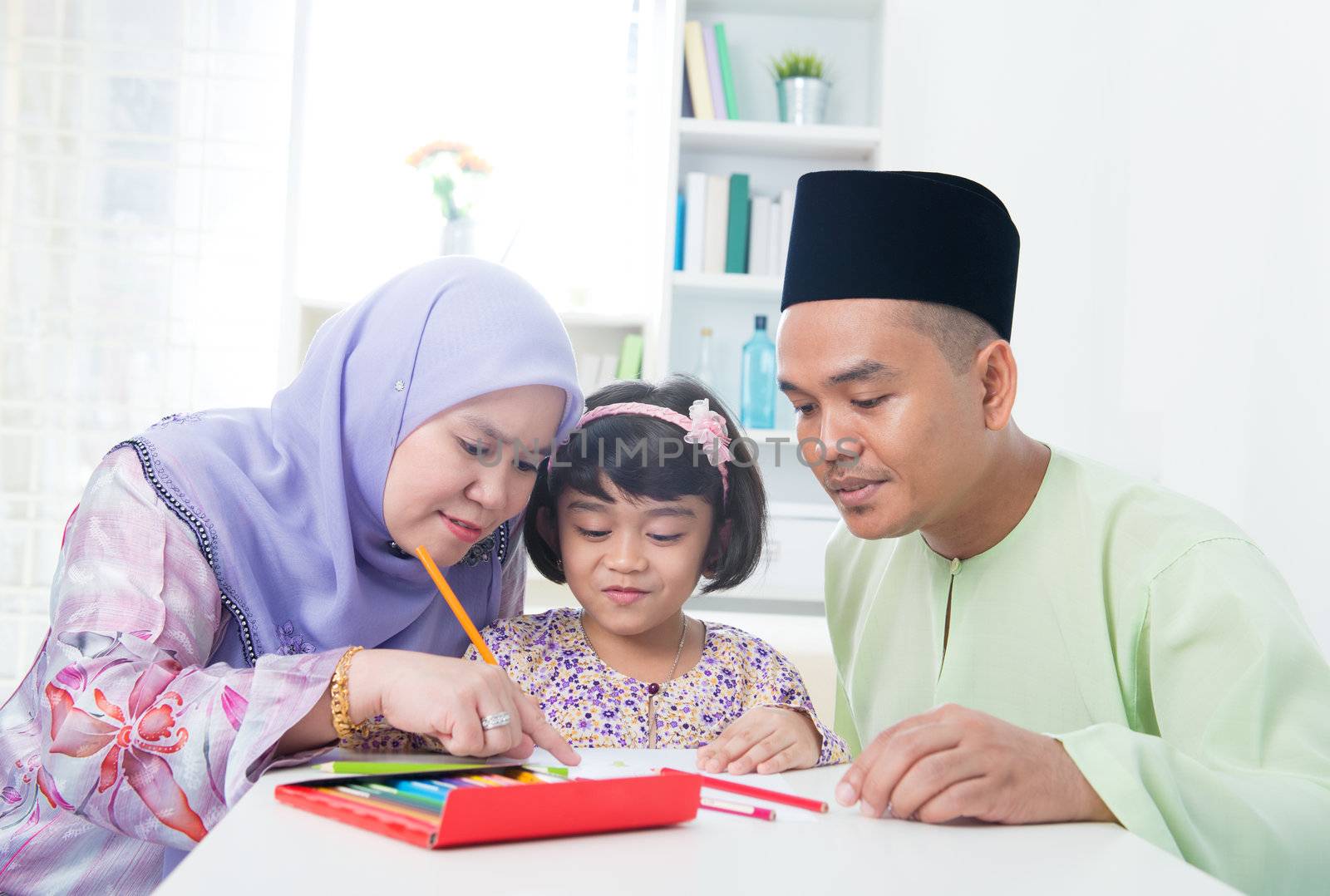 Muslim family drawing picture at home. Southeast Asian family lifestyle.