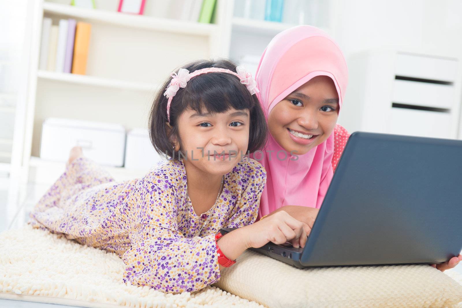 Southeast Asian children surfing internet at home. Malay Muslim girls